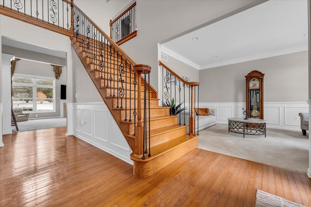 stairway with hardwood / wood-style flooring and crown molding