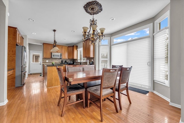 dining space featuring light hardwood / wood-style flooring, a wealth of natural light, and a chandelier