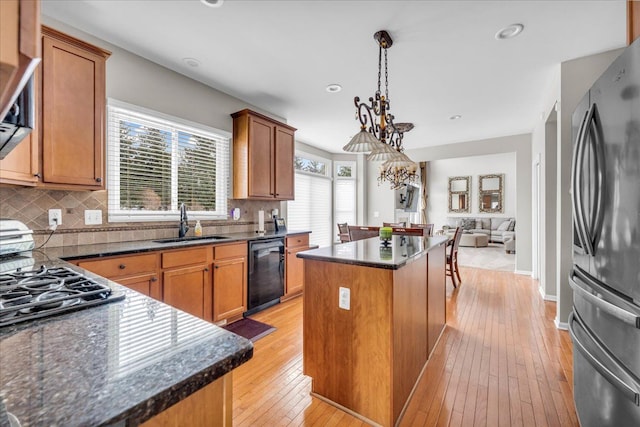 kitchen with sink, decorative light fixtures, a center island, black dishwasher, and stainless steel refrigerator