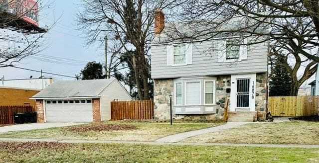 view of property featuring a front yard, a garage, and an outdoor structure