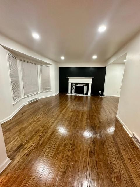 unfurnished living room with hardwood / wood-style flooring, a fireplace, baseboards, and recessed lighting