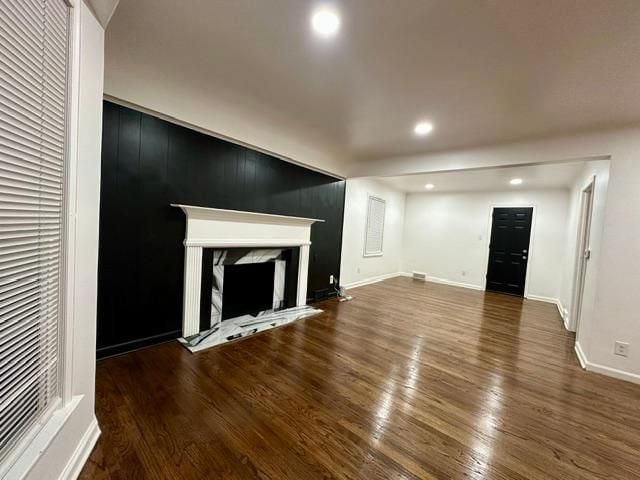 unfurnished living room with a high end fireplace and dark hardwood / wood-style flooring