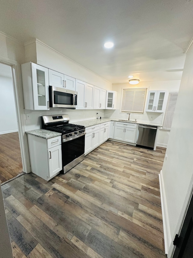 kitchen with stainless steel appliances, white cabinets, and light stone countertops