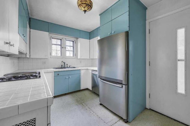 kitchen with sink, backsplash, blue cabinetry, and appliances with stainless steel finishes