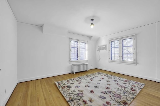 spare room with radiator, hardwood / wood-style floors, and a wall mounted AC