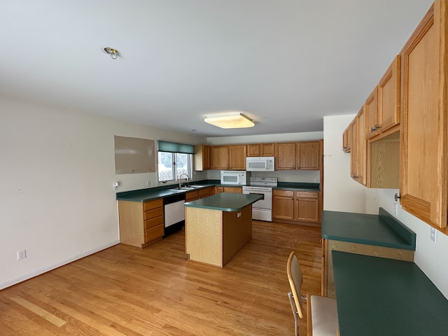 kitchen featuring white appliances, a center island, light hardwood / wood-style flooring, and sink