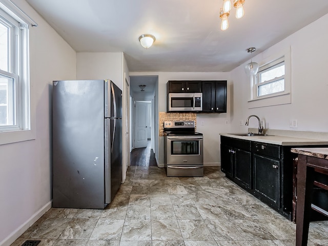 kitchen featuring backsplash, decorative light fixtures, sink, and stainless steel appliances