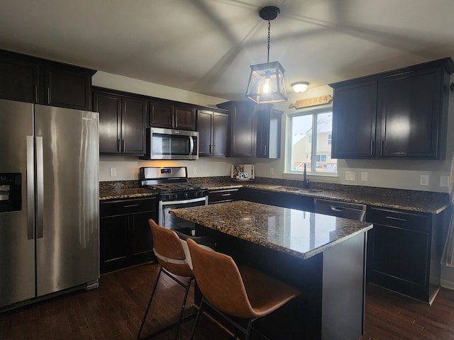 kitchen with sink, a center island, dark hardwood / wood-style flooring, decorative light fixtures, and appliances with stainless steel finishes