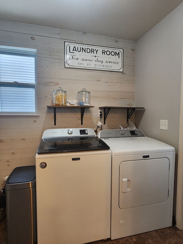 clothes washing area with washing machine and dryer and wooden walls