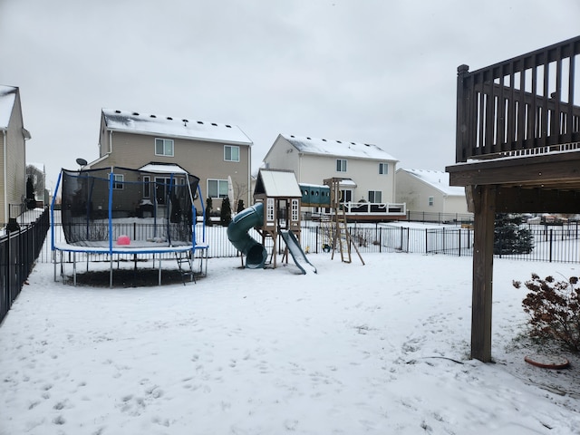 snowy yard featuring a playground and a trampoline