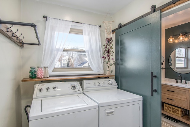 washroom with a barn door, sink, a healthy amount of sunlight, and washing machine and dryer