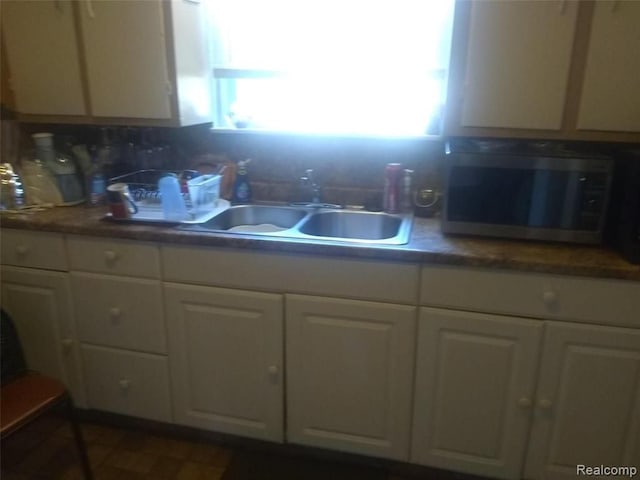 kitchen with tasteful backsplash, white cabinetry, and sink