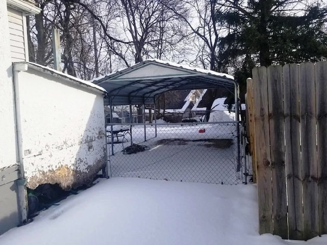 snow covered parking area with a carport