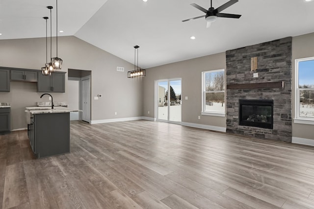 unfurnished living room with lofted ceiling, hardwood / wood-style flooring, a fireplace, and ceiling fan