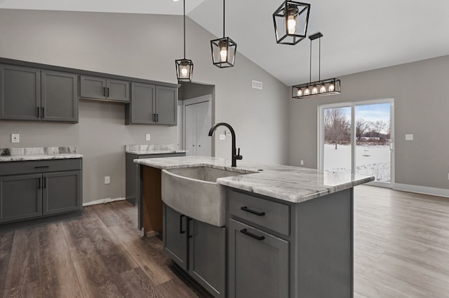 9033 Copper Ridge Dr, Davison, MI 48423 - kitchen with gray cabinets, high vaulted ceiling, light stone countertops, wood finished floors, and decorative light fixtures