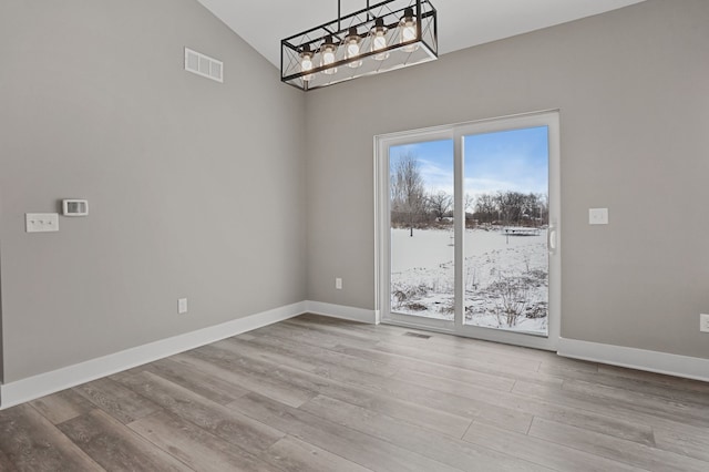 9033 Copper Ridge Dr, Davison, MI 48423 - unfurnished dining area featuring wood finished floors, high vaulted ceiling, and a chandelier