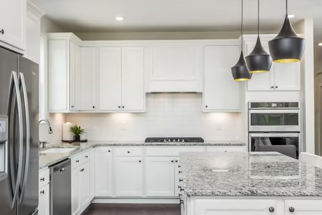 kitchen with stainless steel appliances, white cabinetry, light stone countertops, and pendant lighting