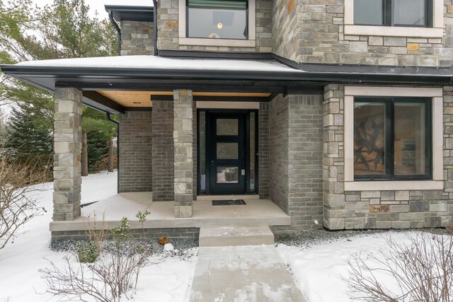 snow covered property entrance with covered porch