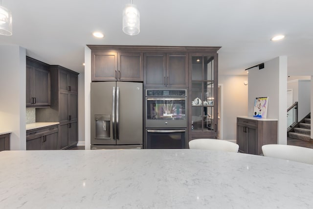 kitchen with stainless steel appliances, dark brown cabinets, pendant lighting, and backsplash