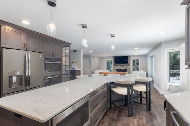 kitchen with pendant lighting, dark hardwood / wood-style floors, stainless steel appliances, and a fireplace