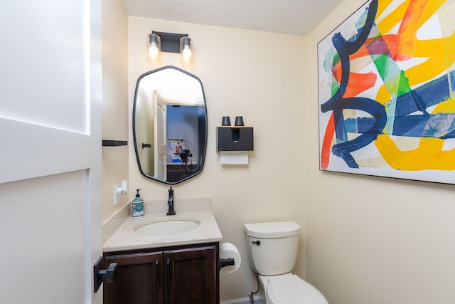 bathroom featuring vanity, a textured ceiling, and toilet