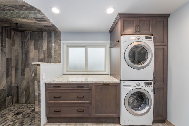 laundry area with cabinets and stacked washing maching and dryer