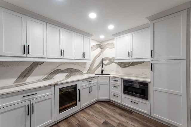 kitchen with white cabinetry, light stone countertops, sink, and wine cooler