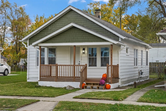 bungalow featuring covered porch and a front yard