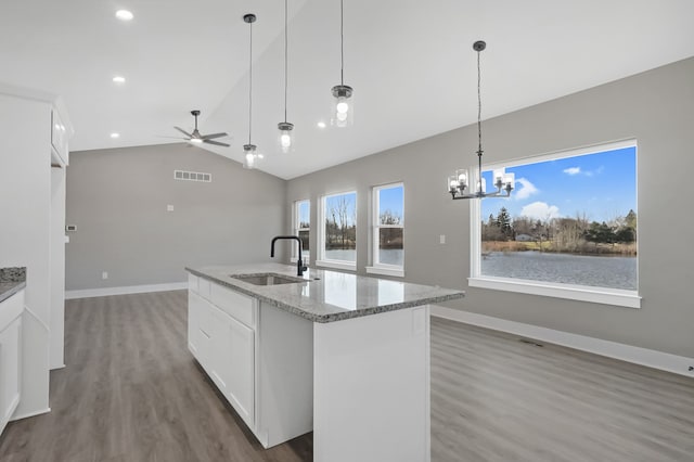 kitchen featuring a water view, a kitchen island with sink, sink, and white cabinets