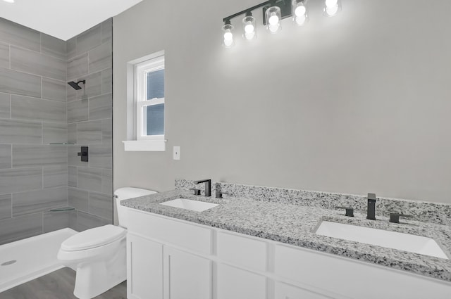 bathroom featuring vanity, toilet, wood-type flooring, and a tile shower