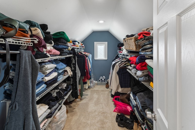 walk in closet with light colored carpet and vaulted ceiling