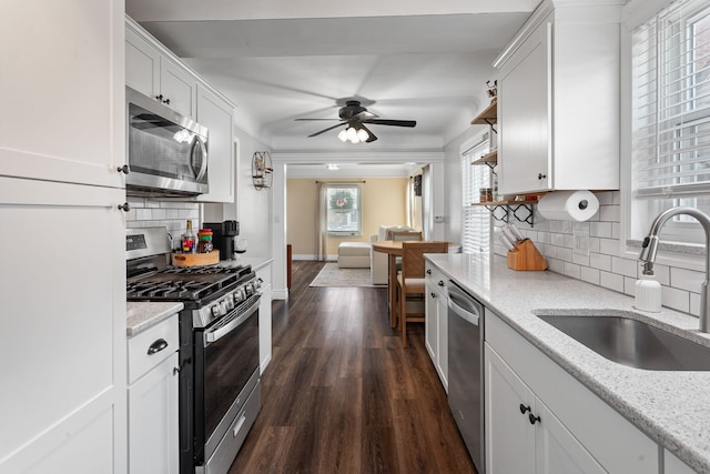 kitchen featuring dark wood-type flooring, sink, light stone counters, appliances with stainless steel finishes, and white cabinets