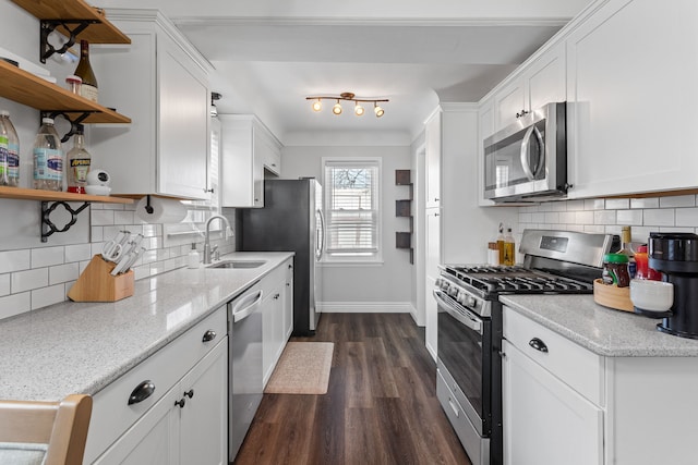 kitchen featuring dark wood-type flooring, sink, white cabinetry, stainless steel appliances, and light stone countertops