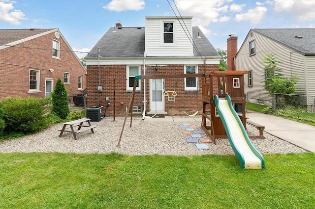 back of property with central AC, a playground, and a lawn