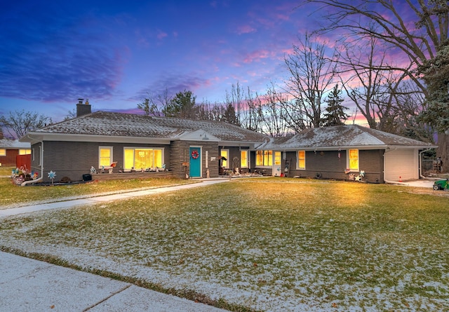 single story home featuring a garage and a lawn