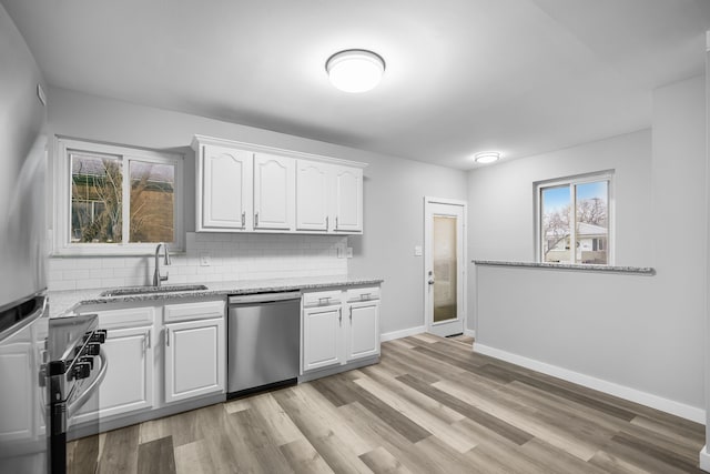 kitchen with white cabinets, appliances with stainless steel finishes, tasteful backsplash, and light stone counters