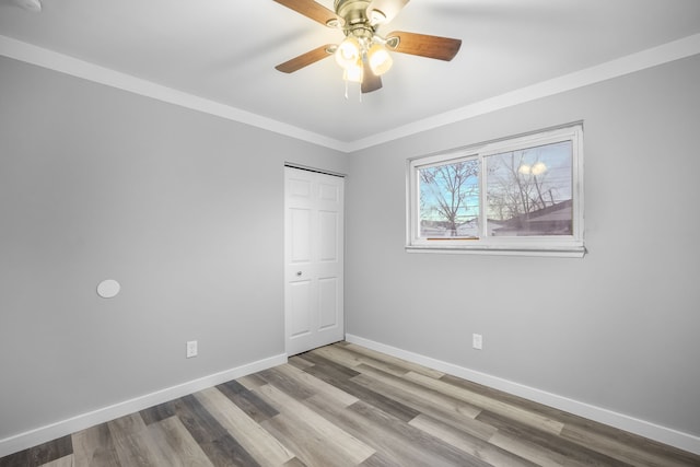 unfurnished bedroom featuring ceiling fan, light wood-type flooring, ornamental molding, and a closet