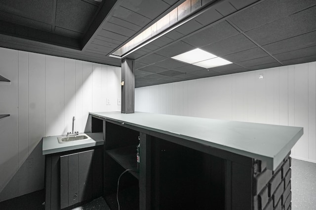 interior space featuring a paneled ceiling, wood walls, and sink