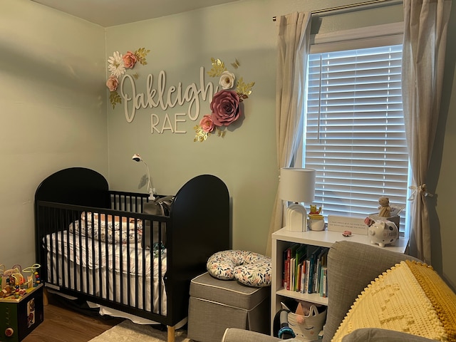 bedroom with wood-type flooring and a crib