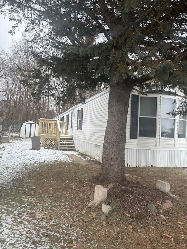 snow covered property with a shed and a deck