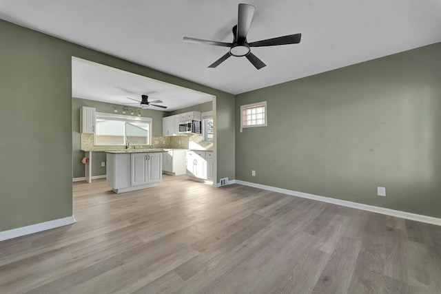 unfurnished living room with light hardwood / wood-style flooring and sink