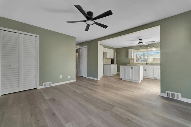 unfurnished living room featuring ceiling fan, light hardwood / wood-style floors, and sink