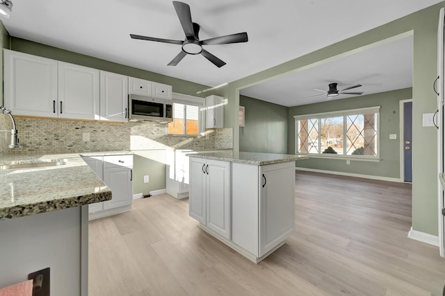 kitchen featuring light stone counters, white cabinetry, sink, and tasteful backsplash