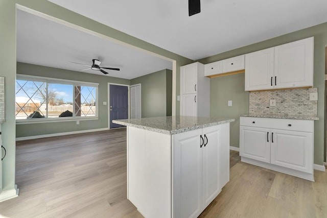 kitchen featuring a center island, light hardwood / wood-style flooring, white cabinetry, and light stone counters