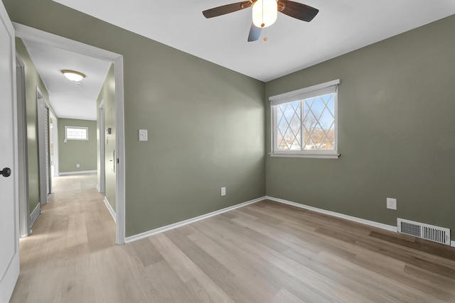 empty room featuring ceiling fan, light wood-type flooring, and a wealth of natural light