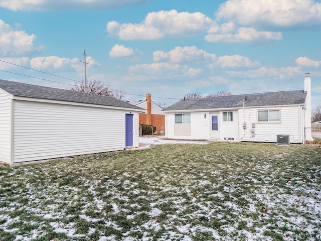 back of property with an outbuilding, central AC unit, and a lawn