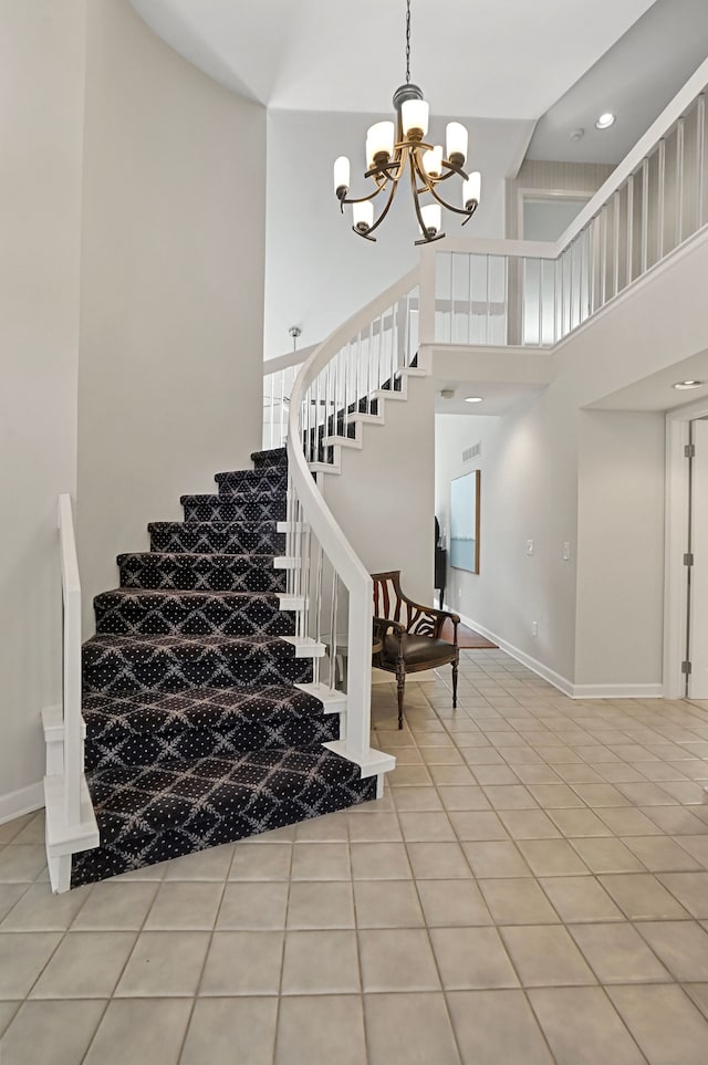 stairs featuring tile patterned flooring, a towering ceiling, and an inviting chandelier