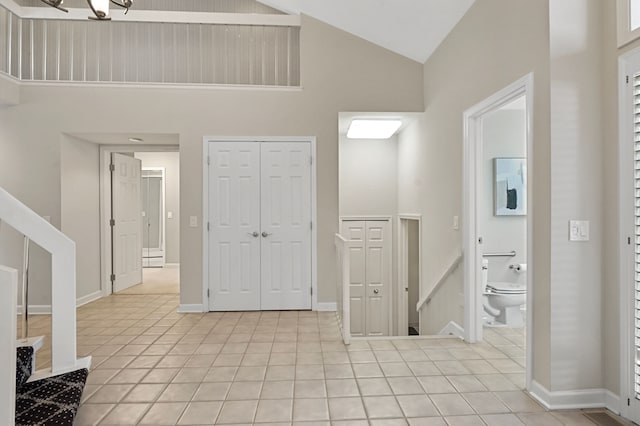 tiled entrance foyer featuring high vaulted ceiling