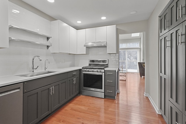 kitchen featuring sink, light hardwood / wood-style flooring, gray cabinets, appliances with stainless steel finishes, and white cabinetry