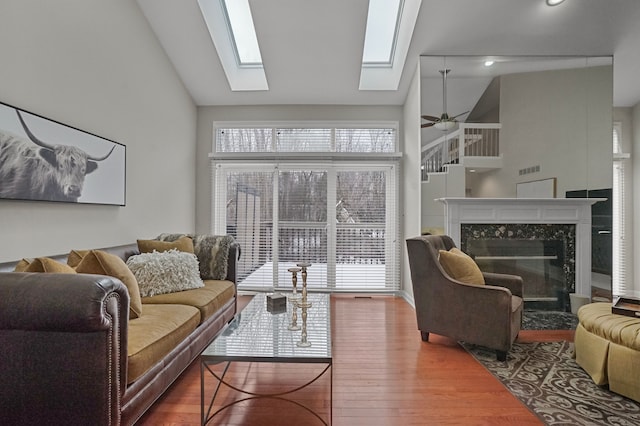 living room with ceiling fan, a high end fireplace, high vaulted ceiling, and hardwood / wood-style flooring